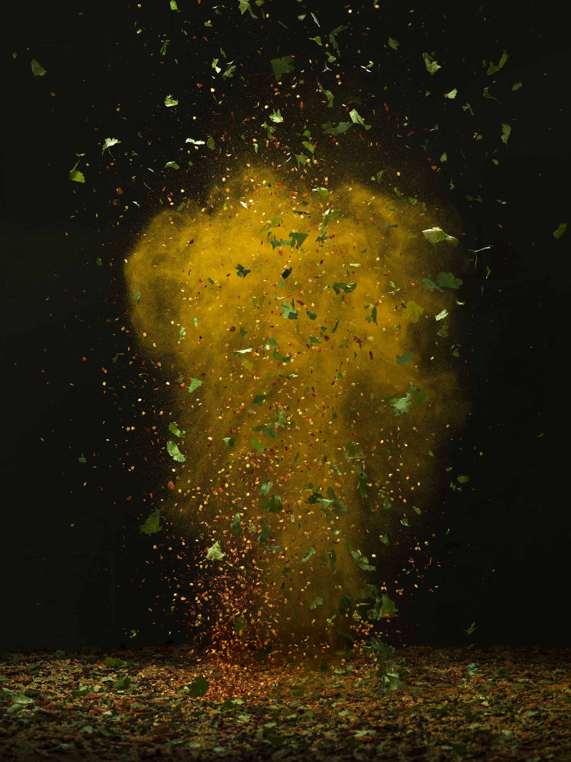 Explosion of Schwartz spices, chillis and coriander on a black background