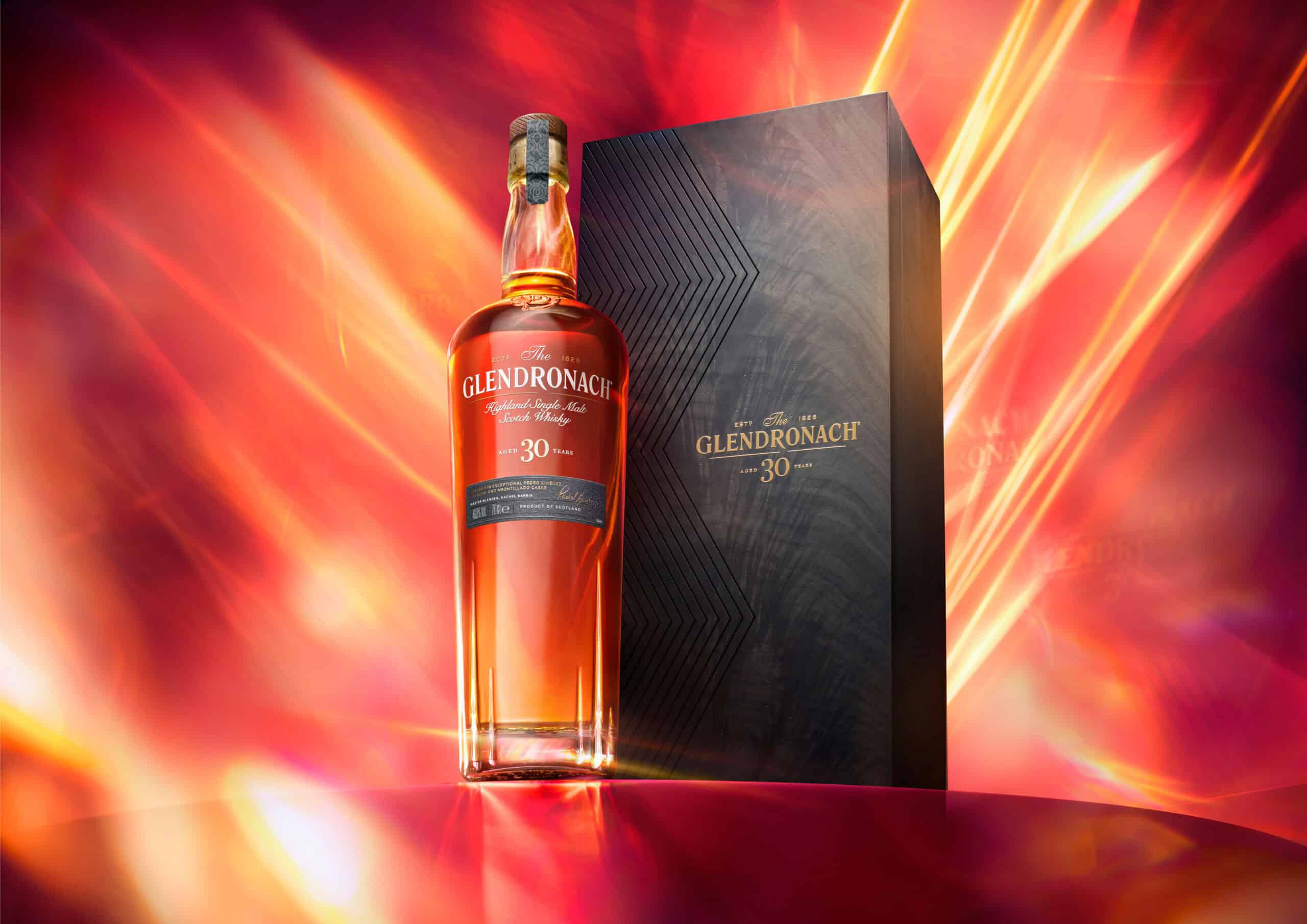 Whisky bottle sitting on a red plinth with a Glendronach black box next to it. The camera angel is low to make the bottle look heroic.