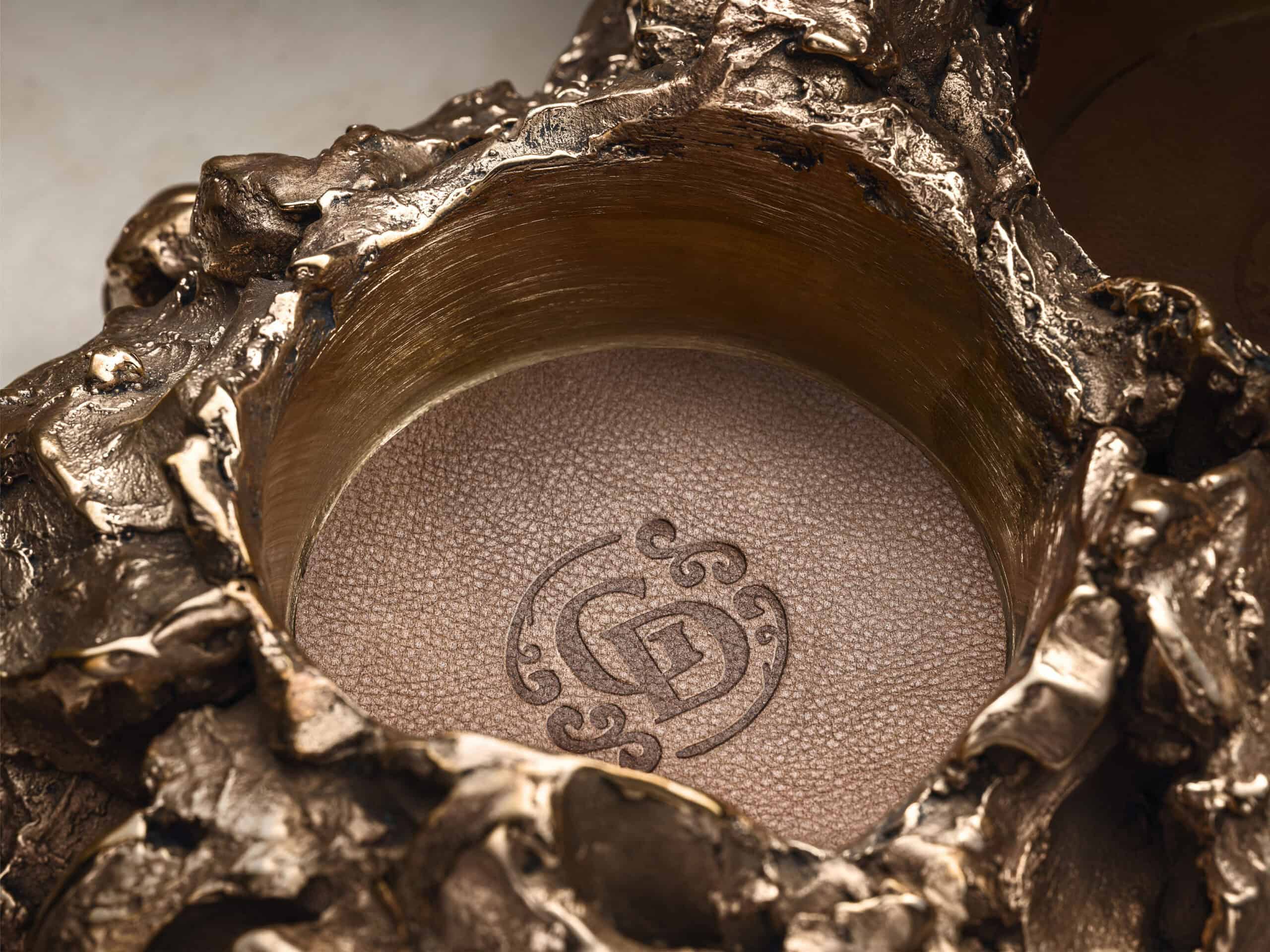 Close-up of a brown leather round pad for a bottle inside a bronze sculpture