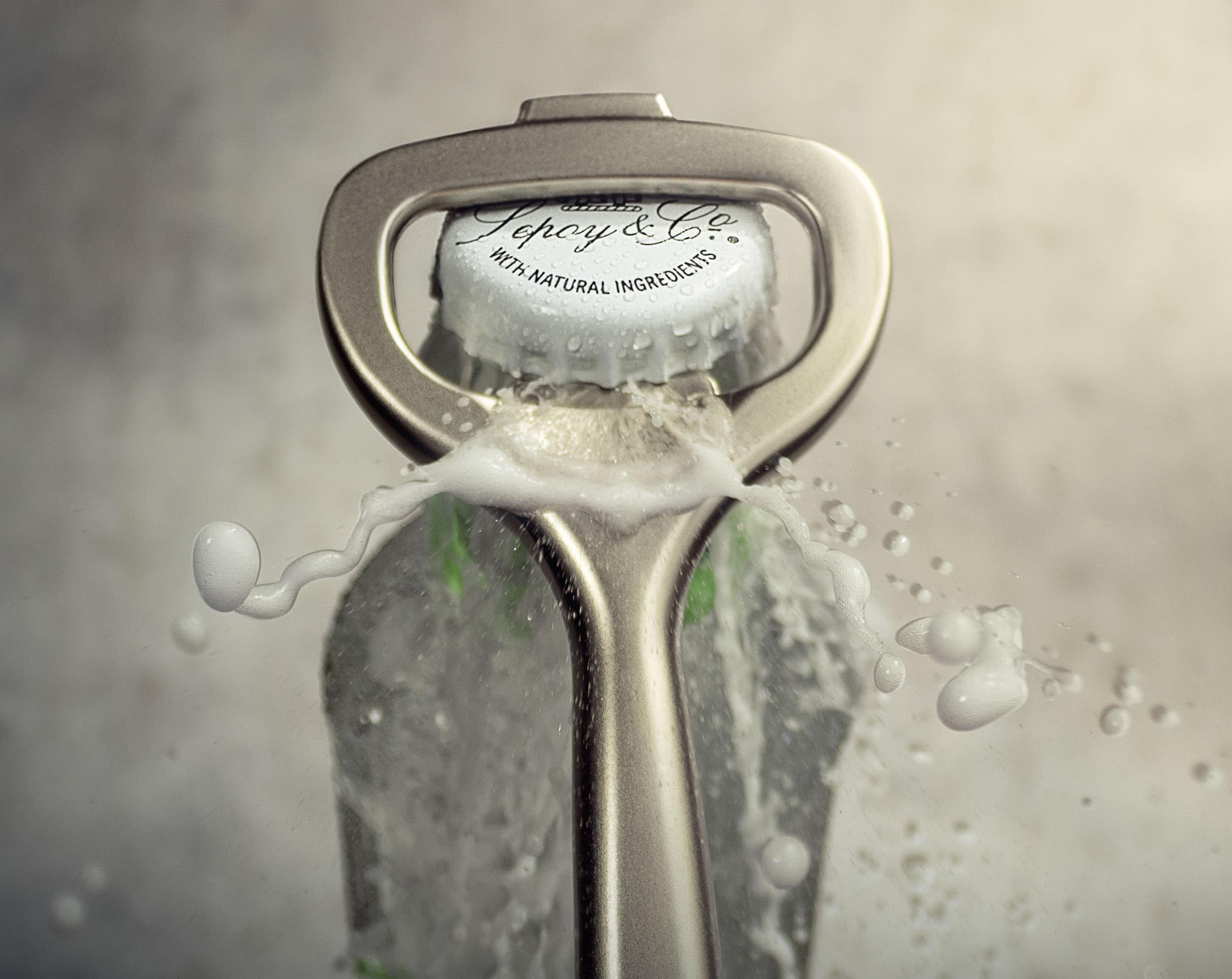 Close-up of a steel bottle opener as it takes the lid off a glass bottle of tonic water. Fizzy liquid and foam bursts through the top of the bottle creating a big splash